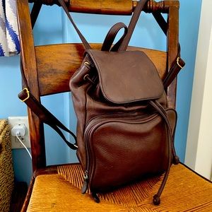 Brown leather drawstring back pack with zippered front pocket.
